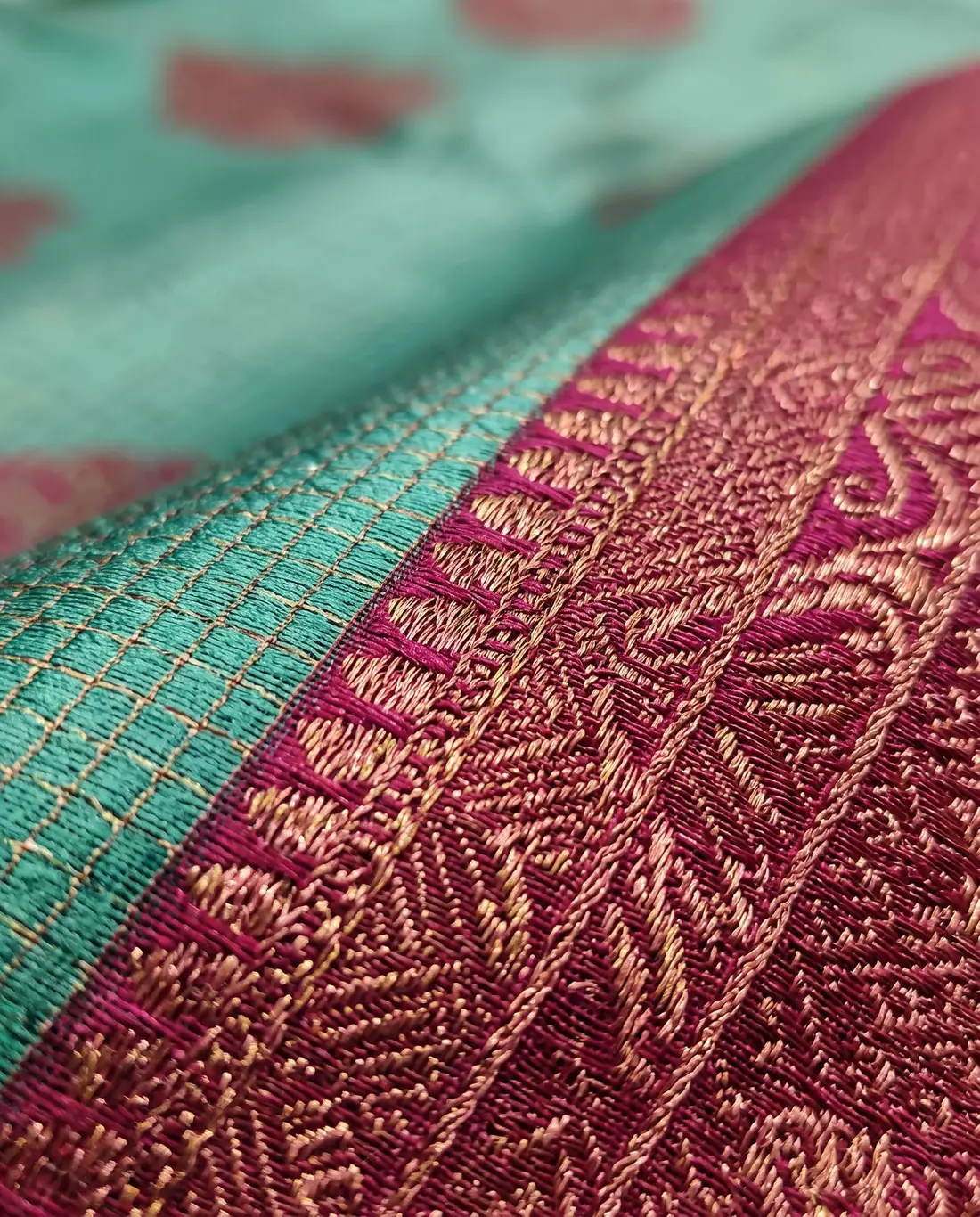 Close-up of a maroon zari border meeting a teal silk body